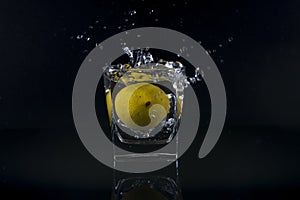 Fresh splash lemon in glass isolated on black