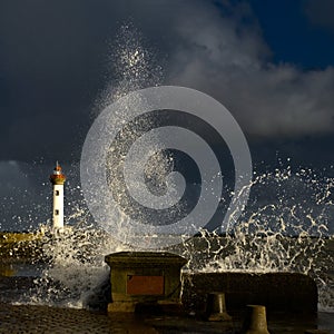 Fresh splash of water next to a lighthouse under the gloomy sky