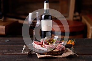 Fresh split lamb ribs on a cutting board with a sealed bottle of red wine and a glass of wine, olive oil with red pepper