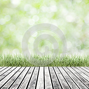 Fresh spring green grass with green bokeh and sunlight and wood