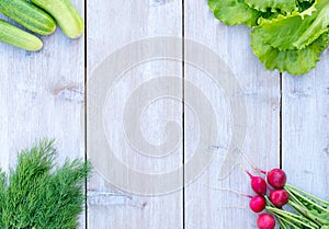 Fresh spring lettuce, green onions and dill , cucumbers radishes on a light wooden background juicy , vegetables , vitamin sa