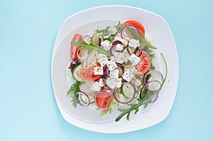 Fresh spring salad with cucumber, tomato, cheese and arugula isolated on a white plate