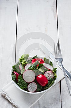 Fresh spring salad with green leaves of arugula, , spinach, beets, radish, cucumber and tomato on a gray stone