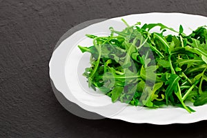 Fresh spring salad with rucola, in bowl on dark stone background