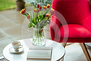 Fresh spring tulips in glass vase and a cup of coffee with a book
