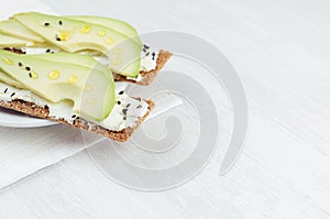 Fresh spring vitamine sandwiches of flat cereal rye dry crisps bread with avocado slices, olive oil, black sesame seeds, cream.