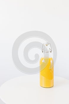 Fresh squeezed orange juice in bottle with stopper on table, white background. Healthy beverage