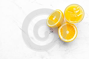 Fresh squeezed orange juice in glass near half cut oranges on white stone background top view copy space