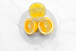 Fresh squeezed orange juice in glass near half cut oranges on white stone background top view space for text