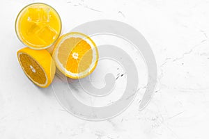 Fresh squeezed orange juice in glass near half cut oranges on white stone background top view space for text