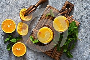 Fresh squeezed orange juice on a gray concrete background with mint