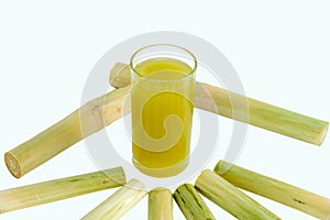 Fresh squeezed sugar cane juice in pitcher with cut pieces cane