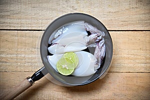 Fresh squid on pan pot top view / Raw squid and lemon lime on wooden background