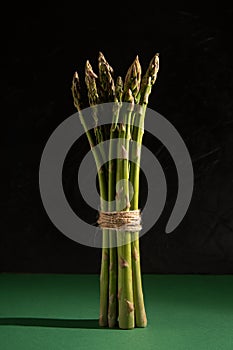 Fresh stalks of green asparagus on a dark green background. Vegan, healthy eating, diet concept. Organic vegetables.