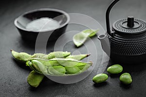 Fresh steamed edamame sprinkled with sea salt on a stone tabletop