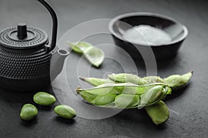 Fresh steamed edamame sprinkled with sea salt on a stone tabletop