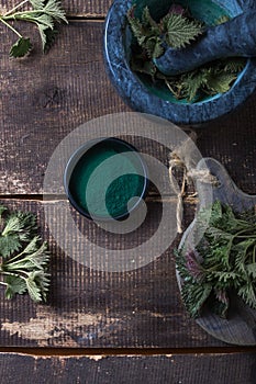 Fresh stinging nettle leaves on wooden table.Urtica dioica oil with spirulina powder, a healthy supplement to improve health photo