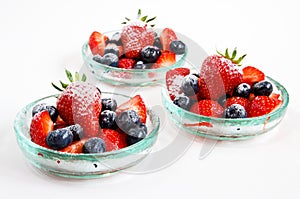 Fresh strawberries and blueberries in glass bowls