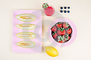 Fresh strawberries in bowl and melone on pastel yellow background.