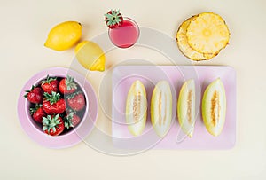 Fresh strawberries in bowl and melone on pastel yellow background.