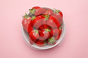 Fresh strawberries in a bowl on pink background