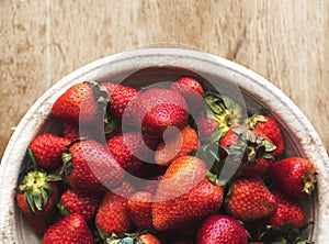 Fresh strawberries in a bowl on wooden table