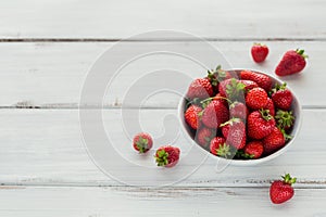 Fresh strawberries on ceramic bowl top view. Healthy food on white wooden table mockup. Delicious, sweet, juicy and ripe berry