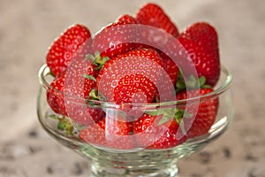 Fresh strawberries in glass bowl. Ripe strawberry closeup. Sweet summer harvest. Juicy dessert. Healthy food. Red berries in vase.