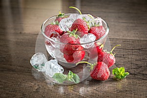 Fresh strawberries with ice cubes in the glass bowl