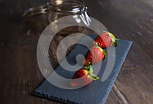 Fresh strawberries still life on slate plate with glass jar and stale base