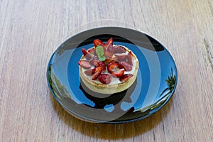 Fresh strawberries on top Cheesecake in black plate on wooden bo