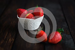 Fresh strawberries in white bowl on old wooden table