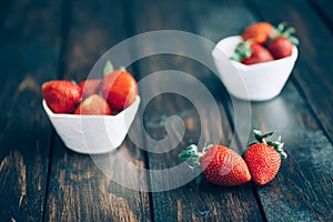 Fresh strawberries in white bowl on old wooden table