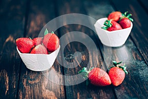Fresh strawberries in white bowl on old wooden table