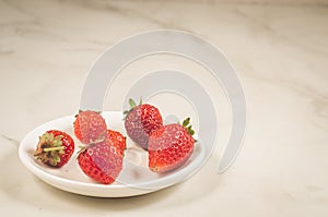 fresh strawberry berries in a bowl/fresh strawberry berries in a bowl on a white marble background, copy space and selective focus