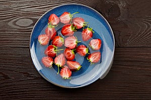 Fresh strawberry in blue plate on dark wooden background