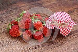 Fresh strawberry with a can of strawberry jam on an old wooden b