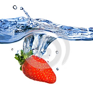 Fresh strawberry dropped into blue water