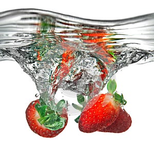 Fresh strawberry dropped into water with splash