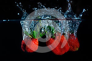 fresh strawberry dropped into water with splash on black backgrounds