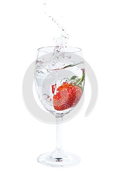 Fresh strawberry dropped into water in wine glass with splash