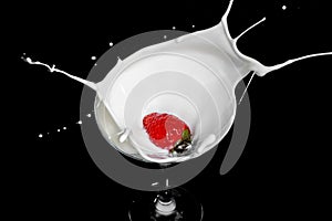 Fresh strawberry falling into glass of milk