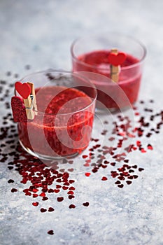 Fresh strawberry margarita or daiquiri cocktail with hearts over gray background, valentine day concepts