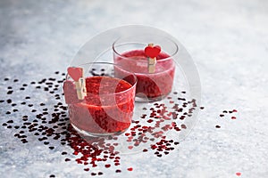 Fresh strawberry margarita or daiquiri cocktail with hearts over gray background, valentine day concepts