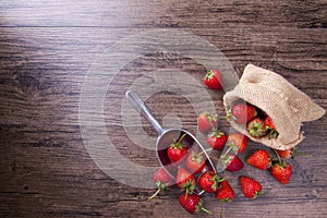 Fresh strawberry in metal ladle on wood table, top view image