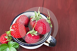 Fresh strawberry in a mug on the wooden brown table