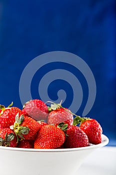 Fresh strawberry in plate on blue background