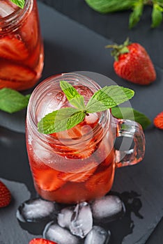 Fresh strawberry smoothie. Fresh summer cocktail with strawberries and ice cubes on a dark background on a black wooden table