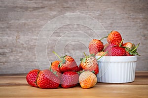 Fresh strawberry in white small bowl on wooden table. Healthy and sweet fruit