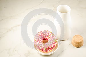 Fresh sugary pink donut and white bottle with milk/fresh sugary